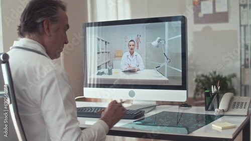 Wallpaper Mural Mature male radiologist in white coat discussing patients X-ray scan with female therapist during video call using computer Torontodigital.ca