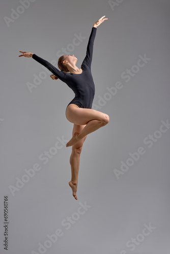 skilled dancer standing on one leg, isolated grey background, hobby, sport interest, woman enjoys her free time, favorite pasttime. full length photo.choreography, being on the height photo