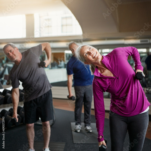 Senior fitness, stretching people with dumbbells at gym for training, wellness or cardio exercise. Class, workout and elderly men with personal trainer for weightlifting club, support or bodybuilding