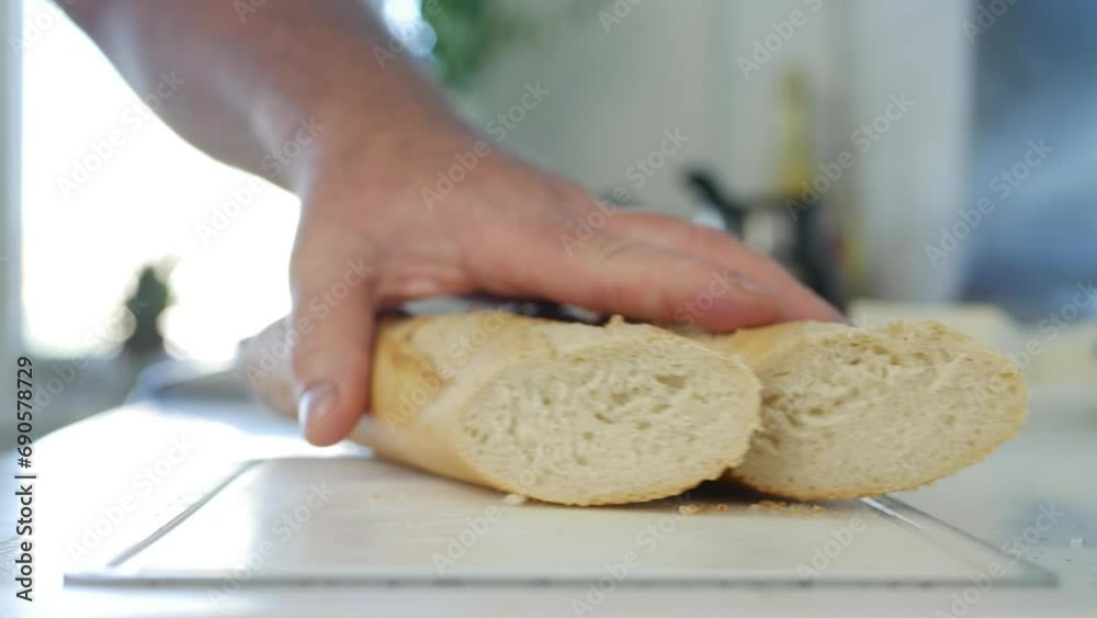 Blurred Shooting with a Man Cutting Slices of Fresh White Bread Using a Knife. Man in the Kitchen Cutting Slices of Bread for Breakfast Sandwiches. Blurred Shooting with a Man Cutting Slices of Fresh White Bread Using a Knife. Man in the Kitchen Cutting Slices of Bread for Breakfast Sandwiches.