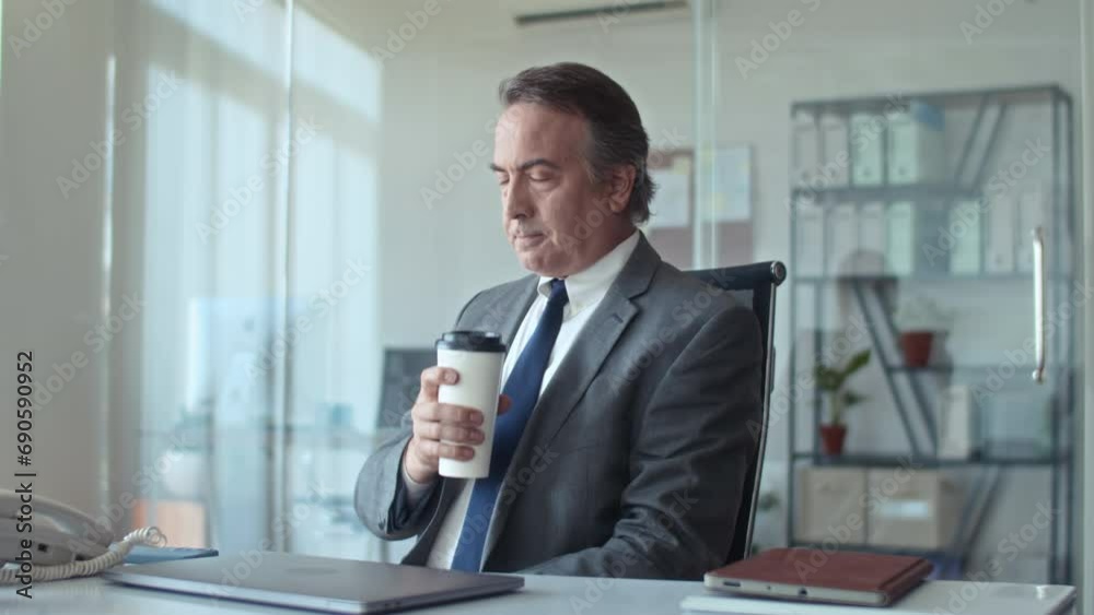 Medium shot of serious head of business department drinking coffee on break at workplace Medium shot of serious head of business department drinking coffee on break at workplace