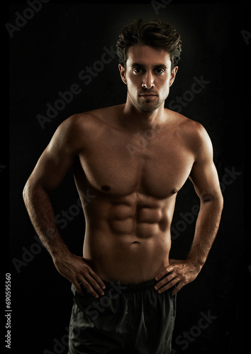 Confident, black background or portrait of man with six pack, strong abs or stomach in studio for fitness. Cool, model or ripped person with healthy body, dark shadow or abdomen muscle for wellness