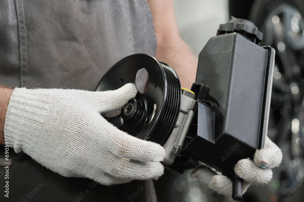 Fototapeta premium A power steering pump is in the hands of an auto mechanic. Inspection of a new product before replacing a defective part.