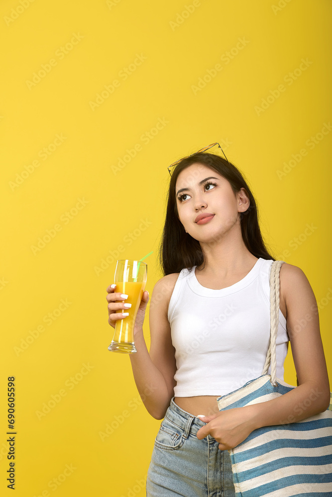 An attractive Asian woman enjoys her vacation in summer, looks up dreamily, enjoys cheerful happiness. Smiling young woman on yellow background An attractive Asian woman enjoys her vacation in summer, looks up dreamily, enjoys cheerful happiness. Smiling young woman on yellow background