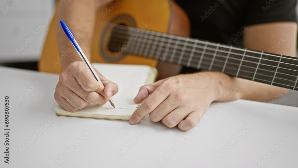 Attractive young hispanic man, a music studio composer artist, captivated by the melody while composing a classic song on his cherished acoustic guitar