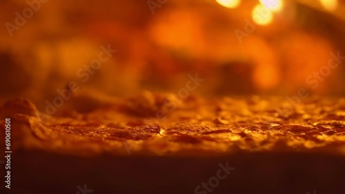 Close-up of pepperoni pizza being unwrapped by pizza maker in a wood stove. Rotating of a fresh tasty pizza with a bubbling cheese during cooking