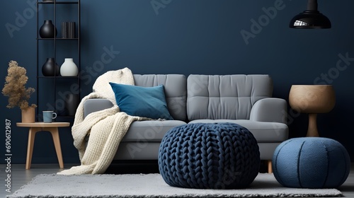 Two knitted poufs near dark blue corner sofa. Scandinavian home interior design of modern living room.