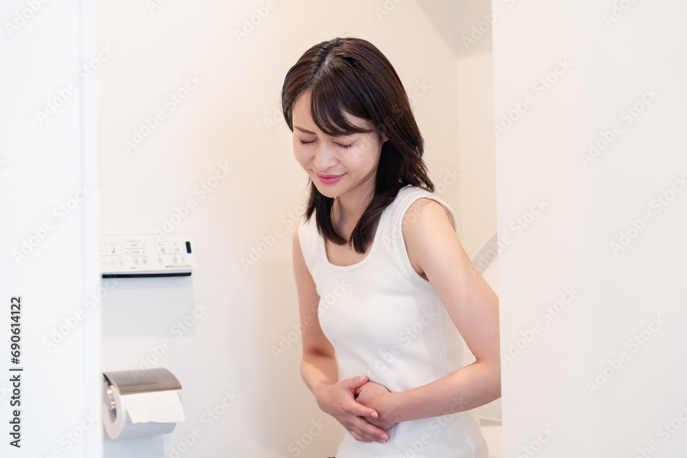 トイレでひどい腹痛に苦しむ若い女性 トイレでひどい腹痛に苦しむ若い女性