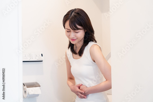 トイレでひどい腹痛に苦しむ若い女性