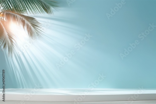 Light blue studio background with shadow from palm leaves on the wall. Rays of the sun on the blue wall. Minimal studio background for product presentations. Spring and summer photo