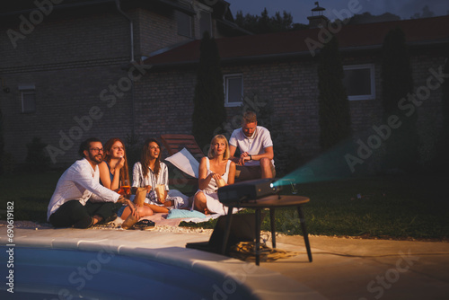 Friends having fun watching a movie in a backyard open air cinema photo