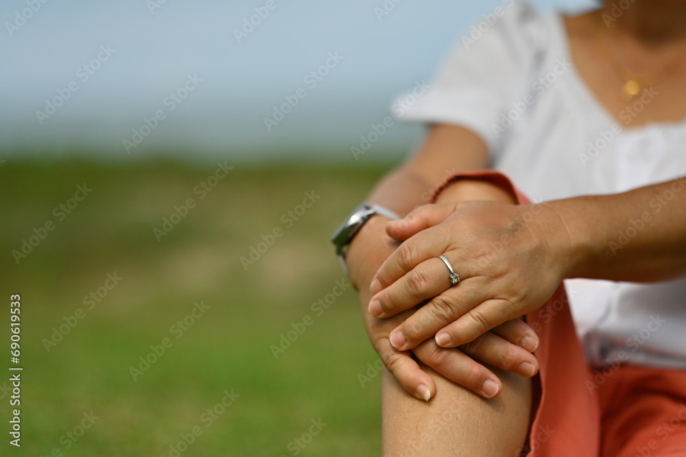 Close-up middle-aged female hands on knees while sitting in a kneeling position