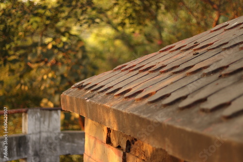 A closeup shot of red Curvy roof shed tile with green trees in the background
