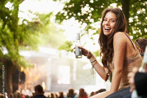 Happy woman, portrait or laughing with drink at music festival, event or outdoor party in nature. Female person smile with alcohol enjoying sound or DJ performance at concert, carnival or summer fest photo