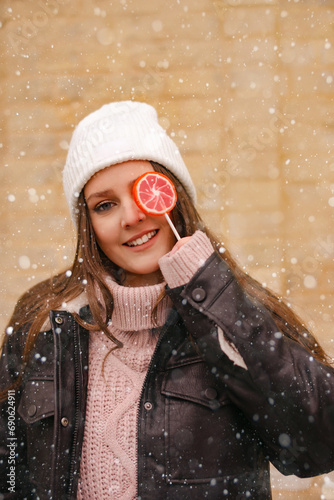young woman have fun and fool around Lollipop Under Falling Snow. Winter holidays outdoors