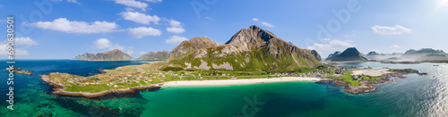 Drone panoramic view of Jusnesvika Bay and Rambergstranda beach in Flakstadoya, Lofoten archipelago, showcasing fantastic contrast of rugged mountains against the turquoise waters and white sands