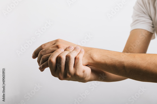 A sad Asian man, his wrist in pain, possibly due to carpal tunnel syndrome, reflects the challenges of arm discomfort. Studio shot isolated on white, illustrating health care and medical issues. photo