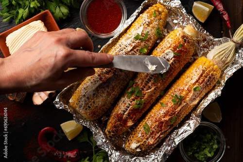 Obraz na płótnie Grilled Sweetcorn with smoked paprika lime and butter on kitchen table being seasoned with table knife flat lay view w salonie