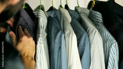 man picks out his outfit from rack of clothes photo