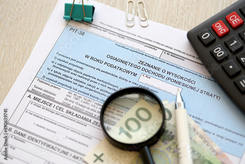 Declaration of the amount of earned income or incurred loss  PIT-38 tax forms on accountant table with pen and polish zloty money bills close up