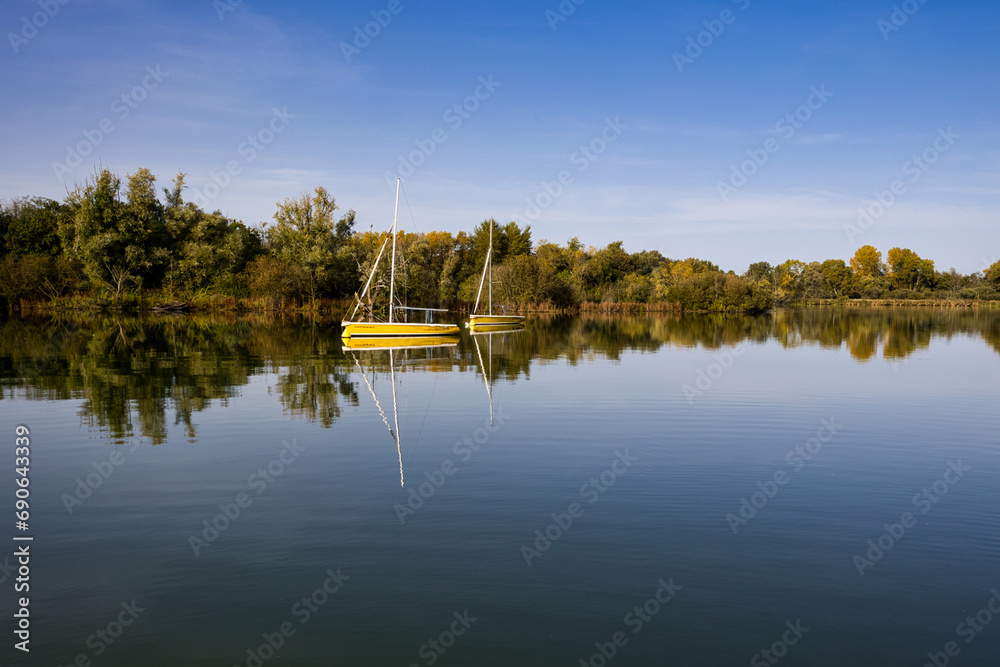 petit bateau de plaisance jaune sur un lac avec un ciel bleu et qui ce reflète dans l eau petit bateau de plaisance jaune sur un lac avec un ciel bleu et qui ce reflète dans l eau