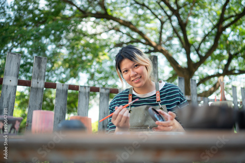 In the pottery workshop, Asian woman is engaged in pottery making and clay painting activities.