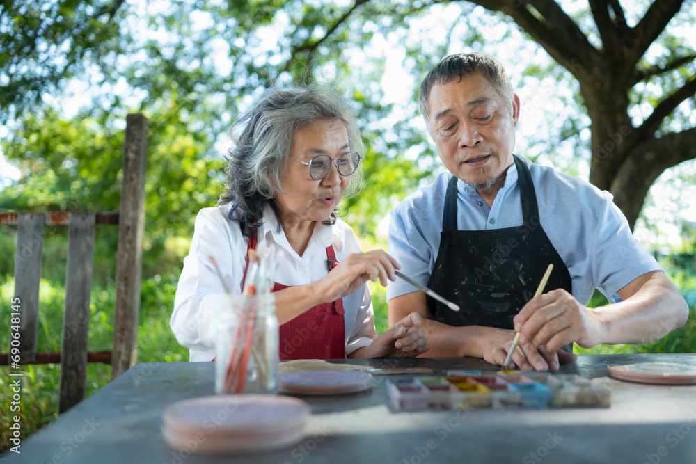 In the pottery workshop, an Asian retired couple is engaged in pottery making and clay painting activities. In the pottery workshop, an Asian retired couple is engaged in pottery making and clay painting activities.
