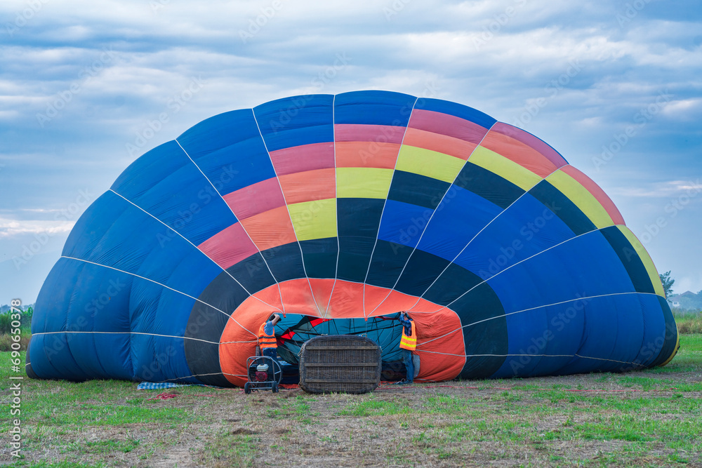 Fototapeta premium Two men prepare a balloon for flight, a basket on its side for flight.