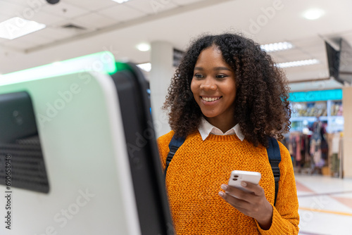 Black woman check-in via automatic machines by herself in the airport to travel or study abroad. photo