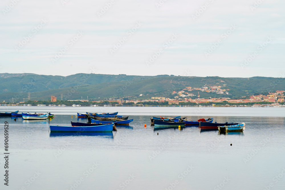 Fototapeta premium Il borgo di Sant'Antioco e le barche dei pescatori visti dallo stagno Santa Caterina. Sardegna, Italia
