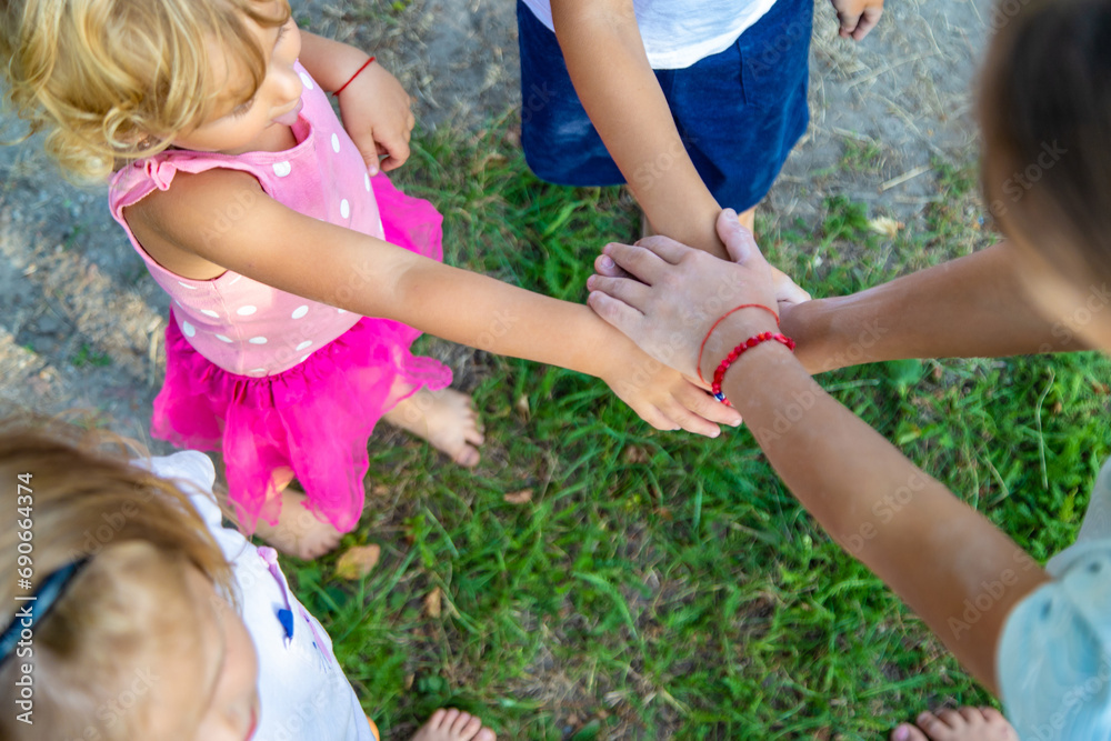 Fototapeta premium a group of children stand together in a circle and fold their hands, team spirit before the game.