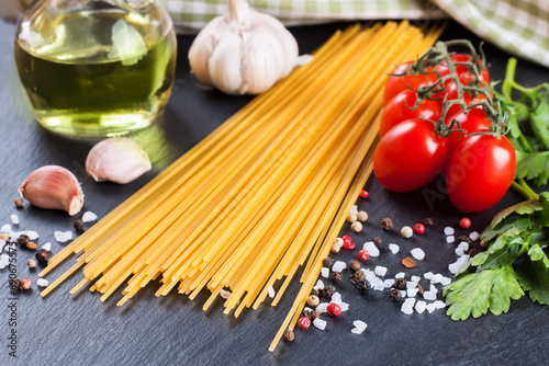 Pasta and food ingredients on black background.