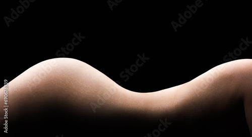 The curve of the silhouette of a female body on a dark background, thin waist and perfect skin. Lateral torso and thighs