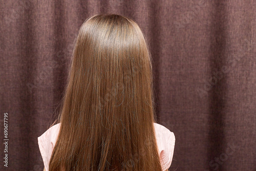 A portrait of a two years old little girl turn back to show her braided hair tied with ribbons.