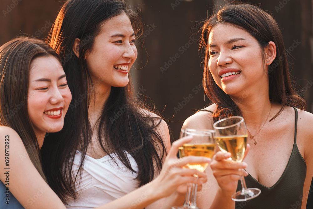 Group of asian woman teenager friends cheering and toast with white sparkling wine glass to celebrating at dinner party in summertime. celebration, anniversary, birthday and friendship concept.