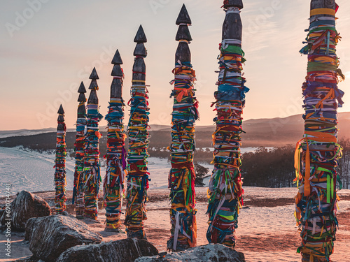 Traditional buryat shaman sacred pillars with colorful ribbons in winter at sunset, cape Burkhan, Olkhon island. Winter Baikal. photo