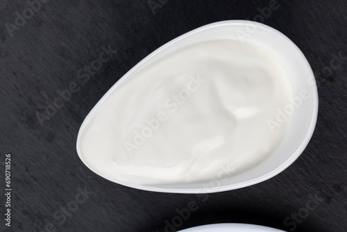 creamy sour cream in a white glass bowl on a black board photo