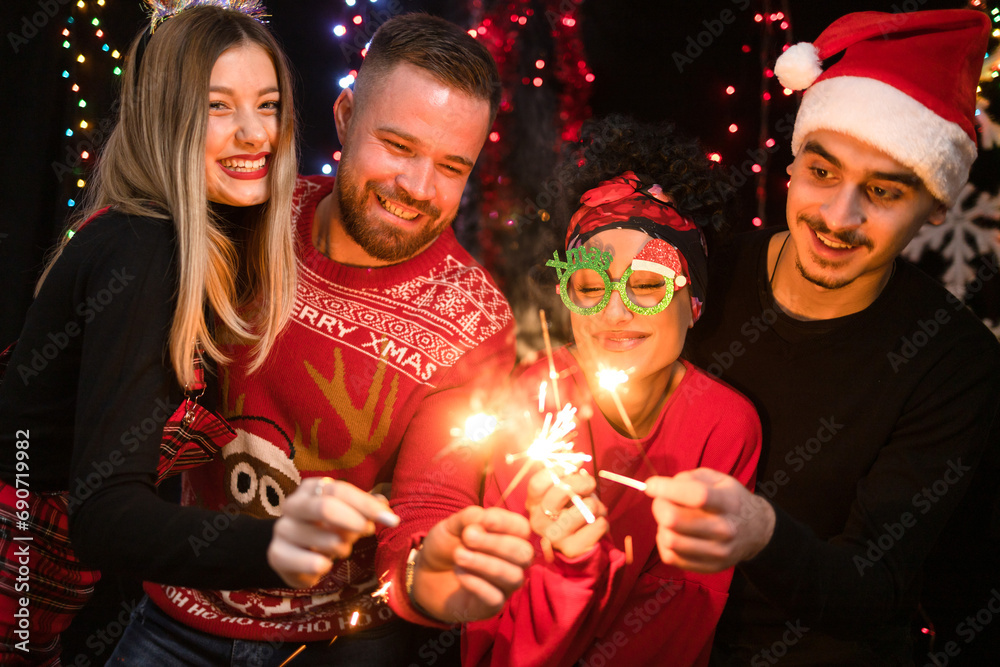 Group of four friends celebrates New Year with sparkles