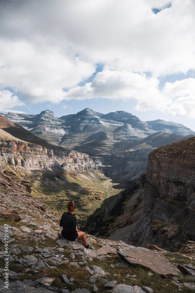 young woman sitting enjoying the landscape of Ordesa y Monte Perdido from the heights of a mountain