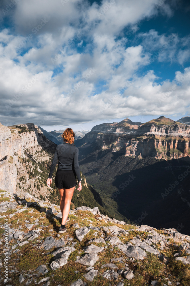 young woman observes from the heights the deep canyon of Ordesa in the Natural Park of the Pyrenees. During a route in summer.