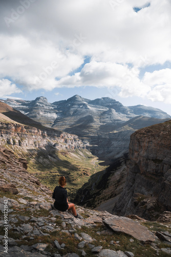 Fotografie young woman sitting enjoying the landscape of Ordesa y Monte Perdido from the he