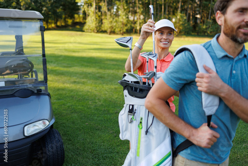 Golfing Partners: Woman Selecting Club from Bag on Course