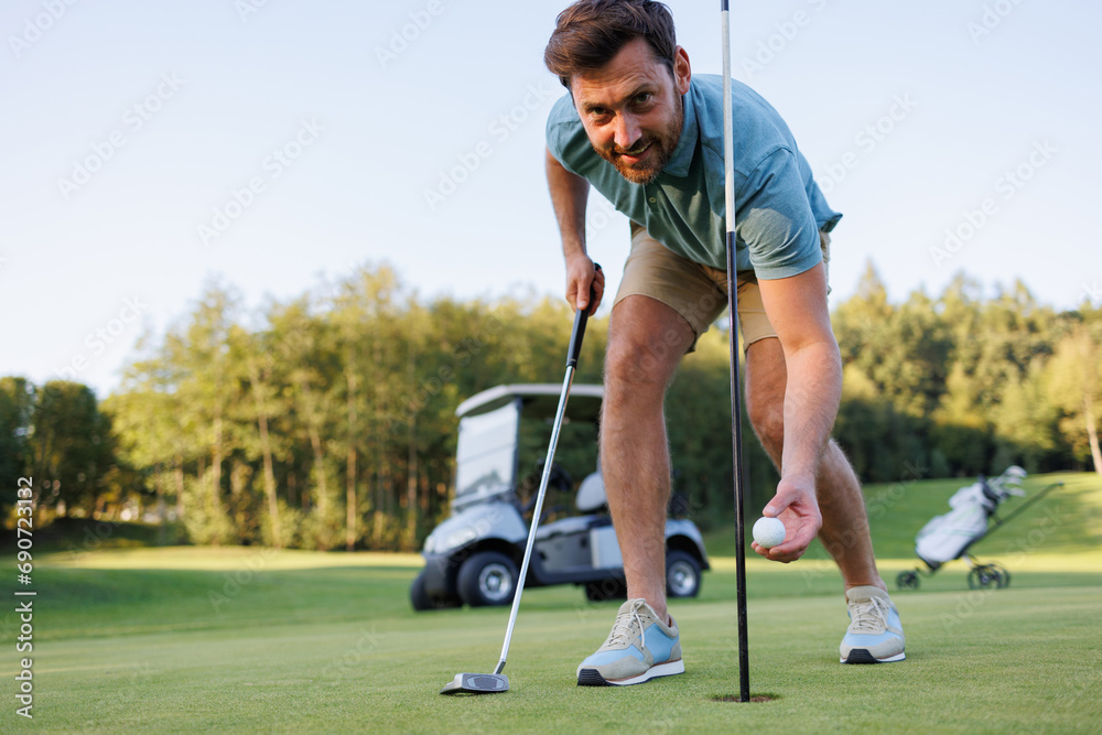 Obraz premium Closing Moments: Golfer Retrieves Ball