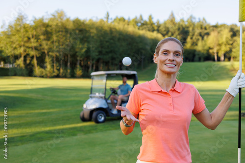 Elated Golfer: Woman Celebrates by Finish Flag, Man Drives Cart