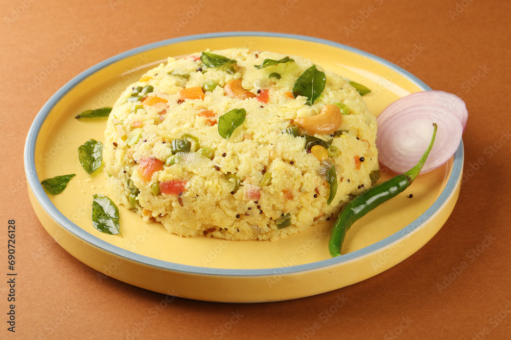 Upma made of samolina or rava upma, most famous south indian breakfast item which is arranged in a black plate and garnished with fried cashew nut and curry leaves 