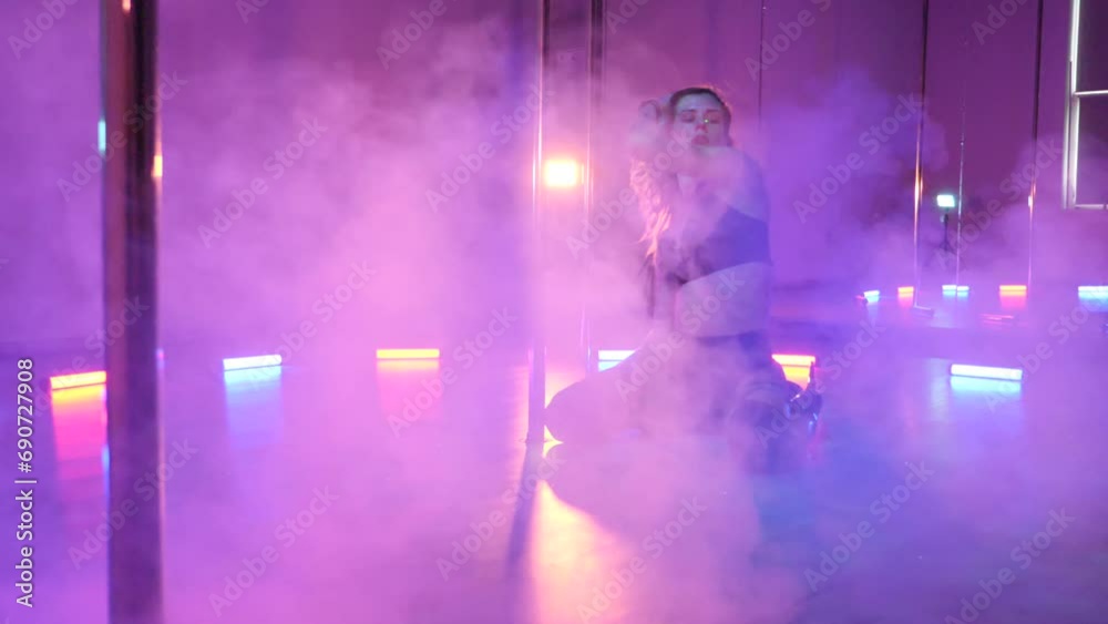 Sexy woman dances a pole dance in a disco club. Erotic dance on a pole