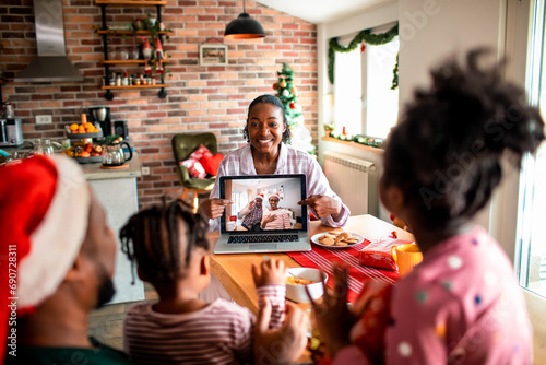 Mother showing video call with grandparents to children at home photo
