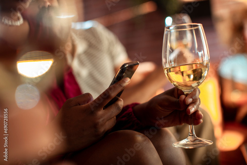 Close up woman using smartphone holding wine glass photo