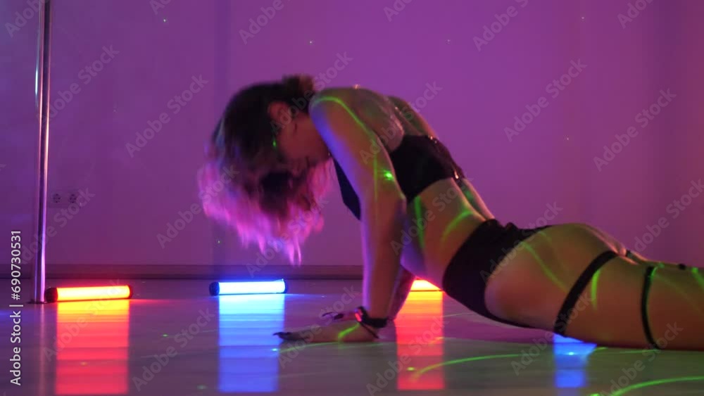 Sexy woman dances a pole dance in a disco club. Erotic dance on a pole