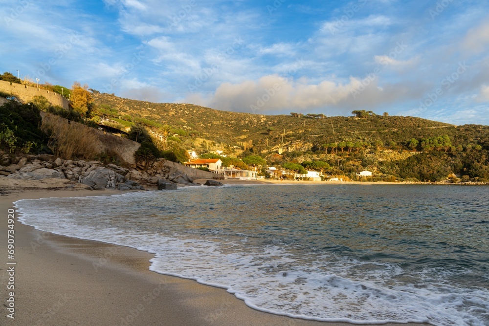 landscape view of Cavoli Beach on Elba in warm evening light and boulders in the foreground